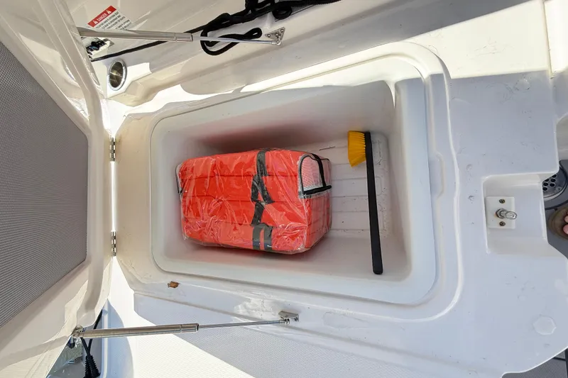 Slide: The Image of Storage compartment in 2023 Chaparral 250 OSX boat with life jacket and brush. - 34