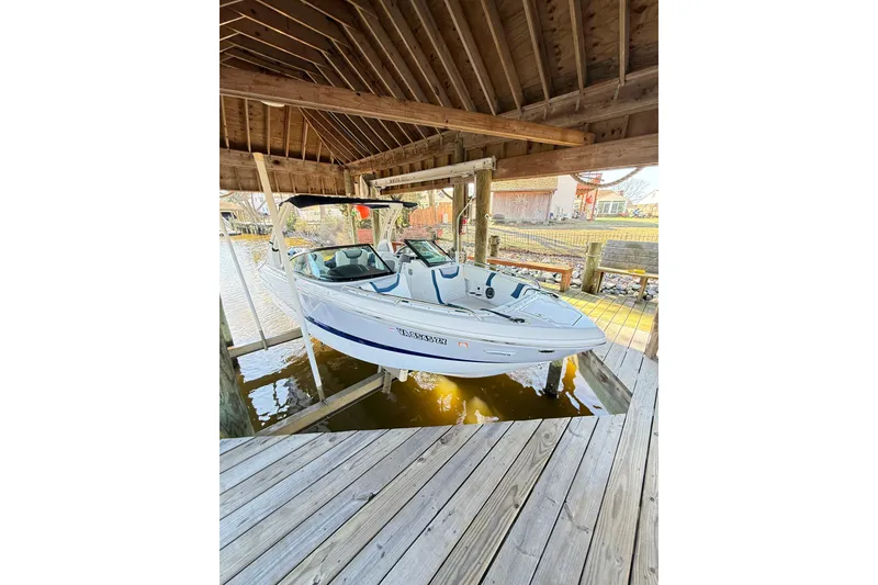 Slide: The Image of 2023 Chaparral 250 OSX boat docked under wooden shelter. - 4