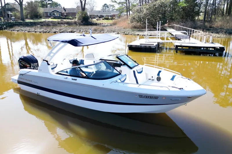 Slide: The Image of 2023 Chaparral 250 OSX boat docked on calm water with scenic background. - 5