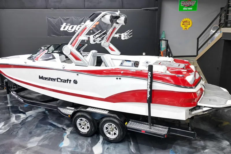 Slide: The Image of 2022 MasterCraft X24 boat in showroom, red and white design, on trailer. - 3