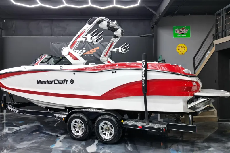 Slide: The Image of 2022 MasterCraft X24 boat in showroom, red and white design, on trailer. - 4
