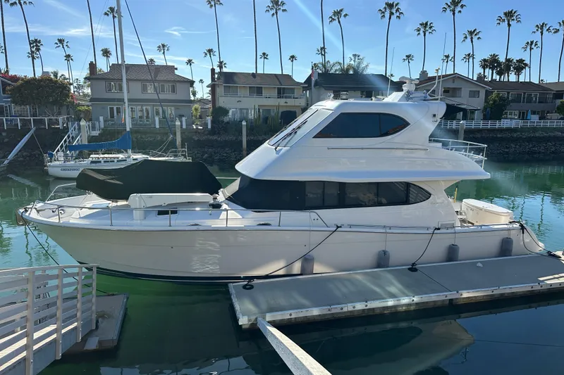 The Image of 2007 Maritimo 52 yacht docked in a serene marina with palm trees and houses. - 1