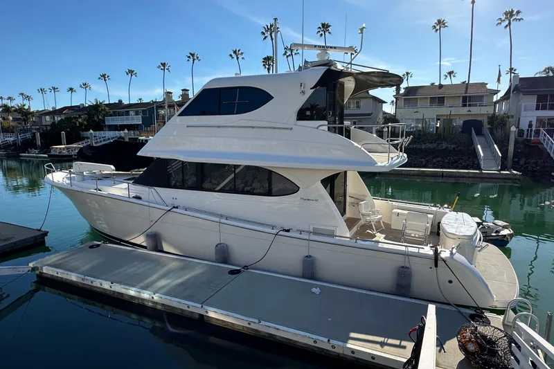 Slide: The Image of 2007 Maritimo 52 yacht docked in a marina, surrounded by palm trees and waterfront homes. - 2