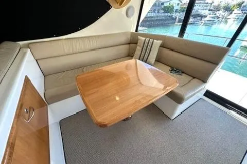 Slide: The Image of 2007 Maritimo 52 yacht interior with beige seating and wooden table by large windows. - 33