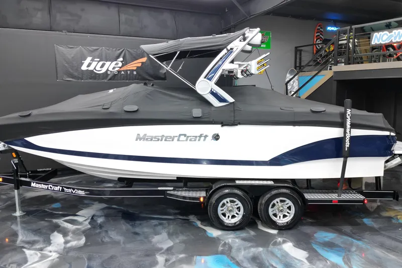 Slide: The Image of 2023 MasterCraft X24 boat on trailer, covered, in showroom setting. - 17