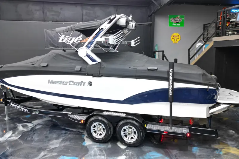 Slide: The Image of 2023 MasterCraft X24 boat with cover on trailer in showroom. - 18