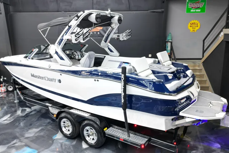 Slide: The Image of 2023 MasterCraft X24 boat on trailer in showroom, featuring sleek design and modern amenities. - 7