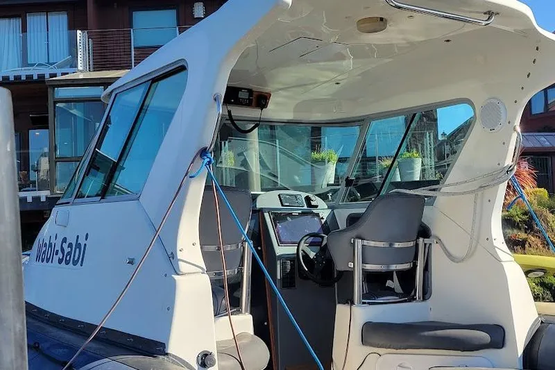 Slide: The Image of 2000 Protector 28 Targa boat interior with steering wheel and seating, docked near buildings. - 3