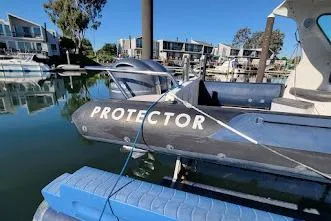 Slide: The Image of 2000 Protector 28 Targa boat docked in a marina with modern waterfront homes. - 8