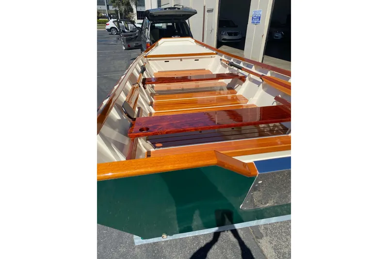 Slide: The Image of Custom 1996 Don boat with polished wooden seats and green exterior, parked outdoors. - 10