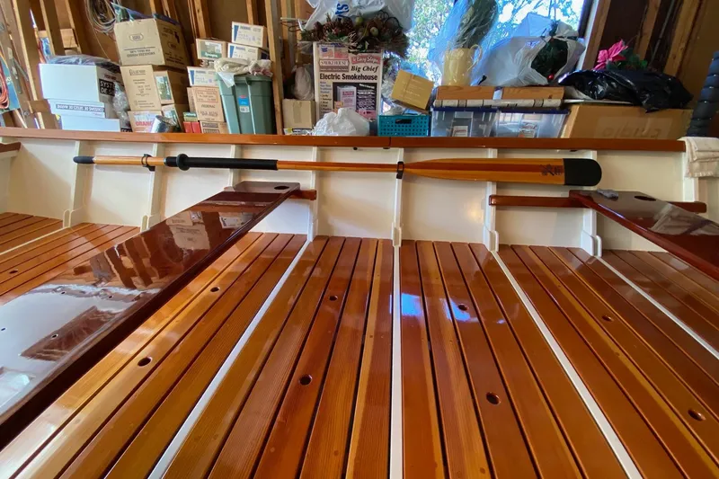 Slide: The Image of Wooden interior of a 1996 Custom Don boat with oars and storage boxes. - 16