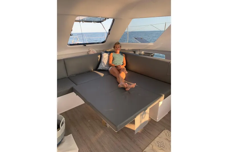 Slide: The Image of Woman relaxing in the interior of a 2022 Seawind 1160 Lite catamaran. - 11
