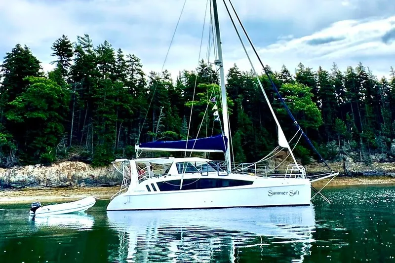 Slide: The Image of 2022 Seawind 1160 Lite catamaran with diesel motors anchored near forested shoreline. - 3