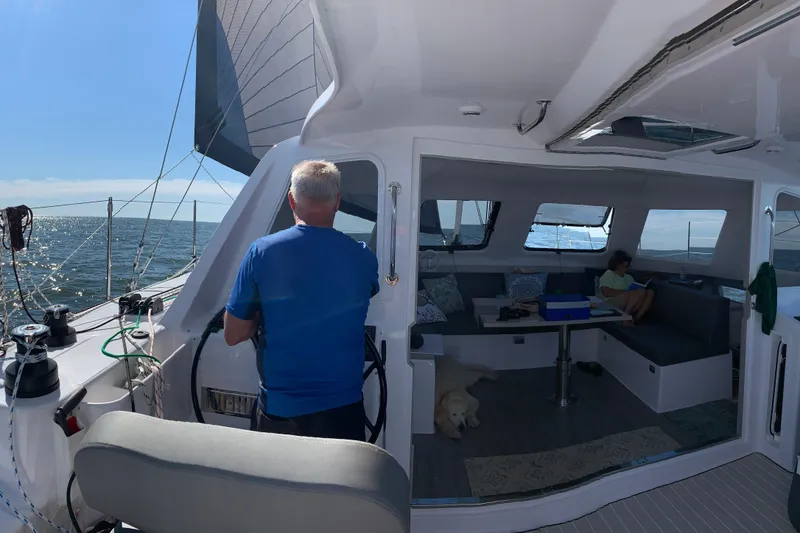 Slide: The Image of Man steering Seawind 1160 Lite catamaran, 2022 model, with interior view and ocean backdrop. - 9