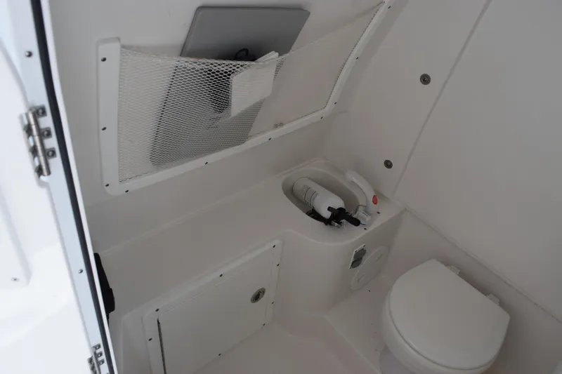 Slide: The Image of Interior of 2023 Sea Hunt Ultra 305 SE boat bathroom with toilet and storage. - 23