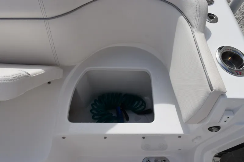 Slide: The Image of 2023 Sea Hunt Ultra 305 SE boat seating with storage compartment and coiled hose. - 31