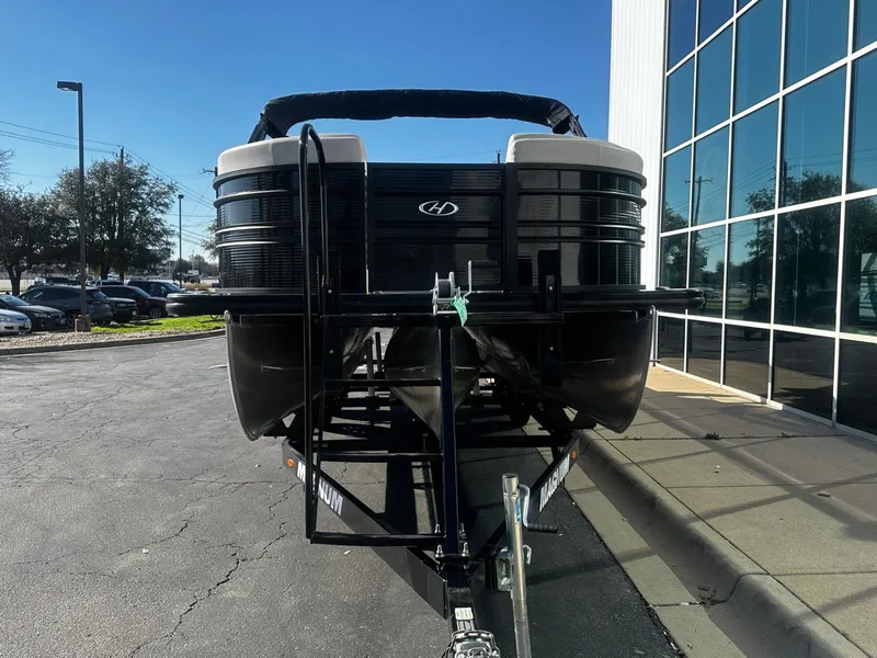 Slide: The Image of 2022 Harris Sunliner 250 pontoon boat on trailer in front of building. - 6