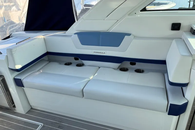 Slide: The Image of 2025 Formula 380 Super Sport Crossover OB boat seating with cup holders and blue accents. - 21