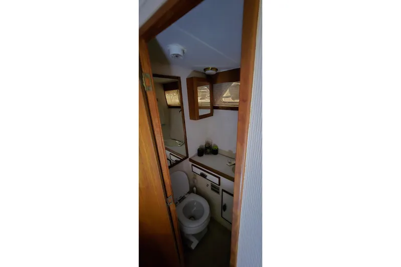 Slide: The Image of 1986 Tollycraft 34 Sundeck bathroom with toilet, sink, and wooden cabinetry. - 23