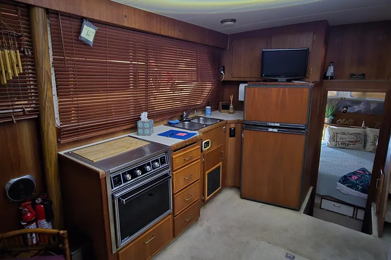 Slide: The Image of 1986 Tollycraft 34 Sundeck interior with kitchen, wooden cabinets, and cozy bedroom view. - 29