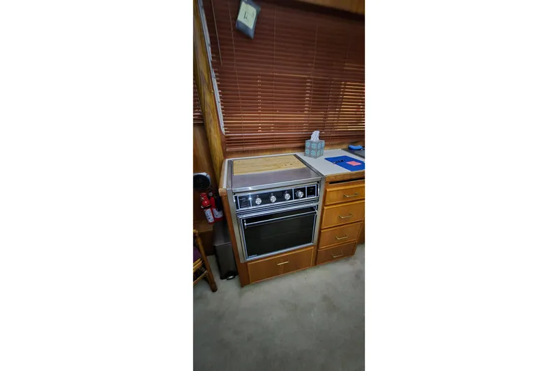 Slide: The Image of 1986 Tollycraft 34 Sundeck kitchen with stove, wooden cabinets, and blinds. - 30