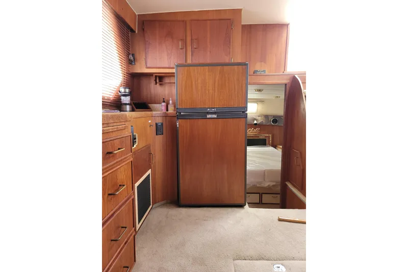Slide: The Image of 1986 Tollycraft 34 Sundeck interior with wooden cabinetry and refrigerator. - 52