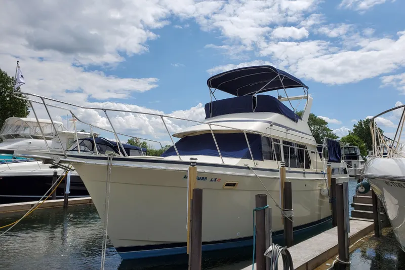 The Image of 1986 Tollycraft 34 Sundeck yacht docked under a partly cloudy sky. - 0