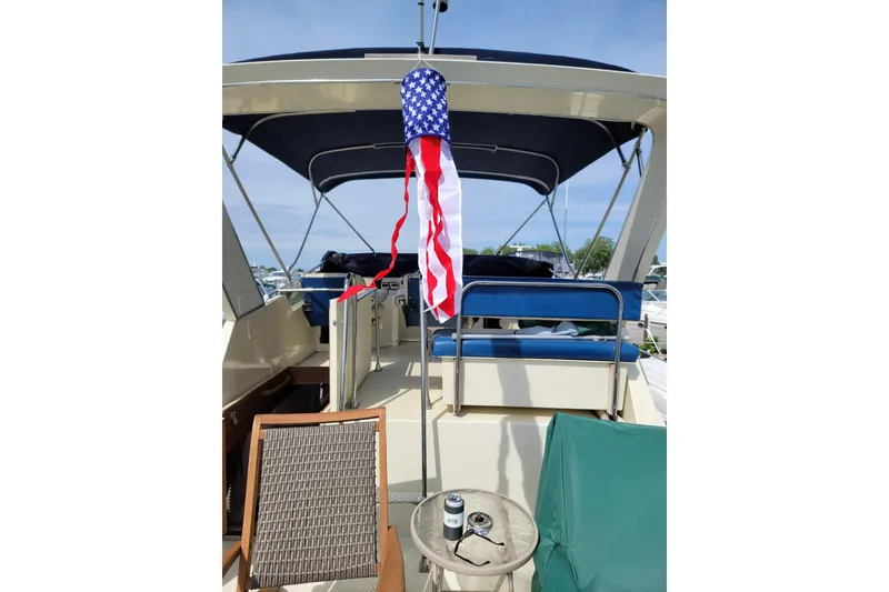 Slide: The Image of 1986 Tollycraft 34 Sundeck with American flag, outdoor seating, and canopy. - 15