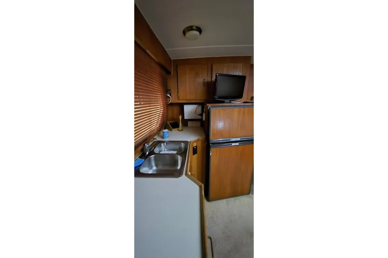 Slide: The Image of 1986 Tollycraft 34 Sundeck interior with kitchenette, sink, and wooden cabinetry. - 32