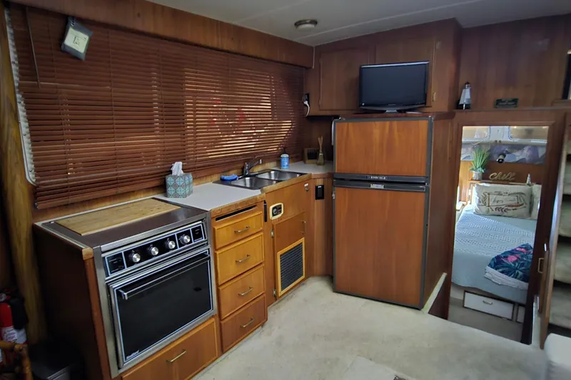 Slide: The Image of 1986 Tollycraft 34 Sundeck interior with kitchen, wooden cabinets, and cozy bedroom view. - 47