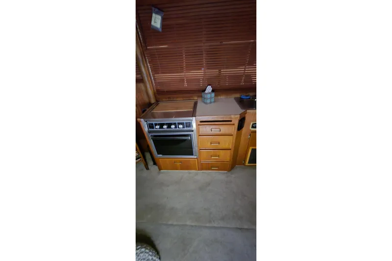 Slide: The Image of 1986 Tollycraft 34 Sundeck kitchen with stove, wooden cabinets, and blinds. - 49