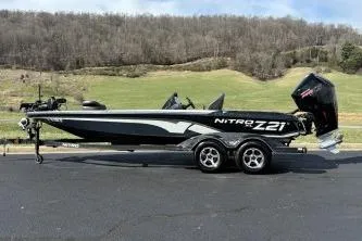Slide: The Image of 2023 Nitro Z21 XL boat on trailer, parked on asphalt with scenic background. - 10