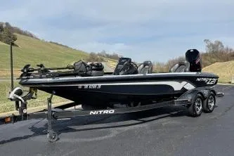 Slide: The Image of 2023 Nitro Z21 XL boat on trailer, parked on paved road, scenic background. - 11