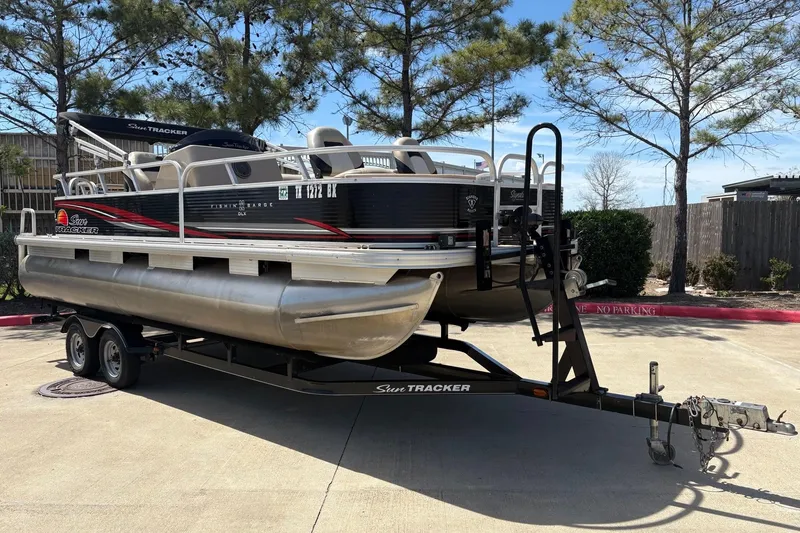 The Image of 2013 Sun Tracker Fishin' Barge 22 DLX pontoon boat on trailer, parked outdoors. - 1