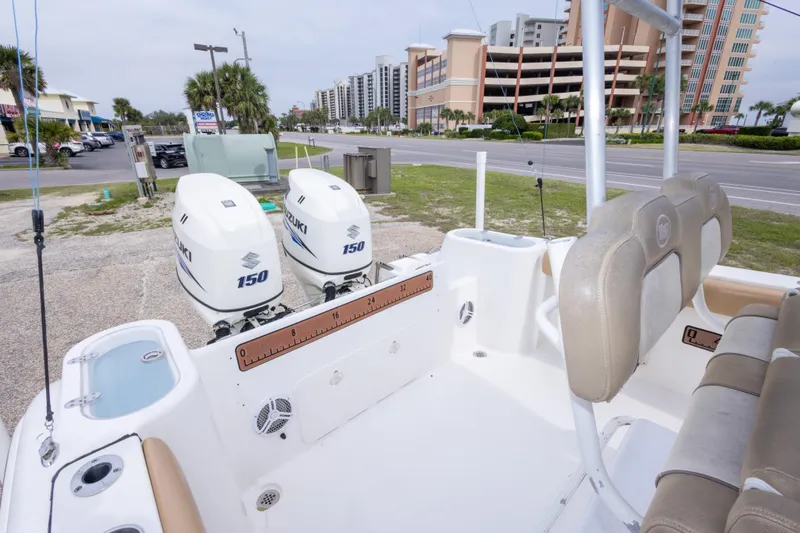 Slide: The Image of 2016 Key West 244 Center Console boat with dual Suzuki 150 engines, parked near buildings. - 18