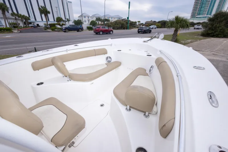 Slide: The Image of 2016 Key West 244 Center Console boat with beige seating, parked near a road. - 24