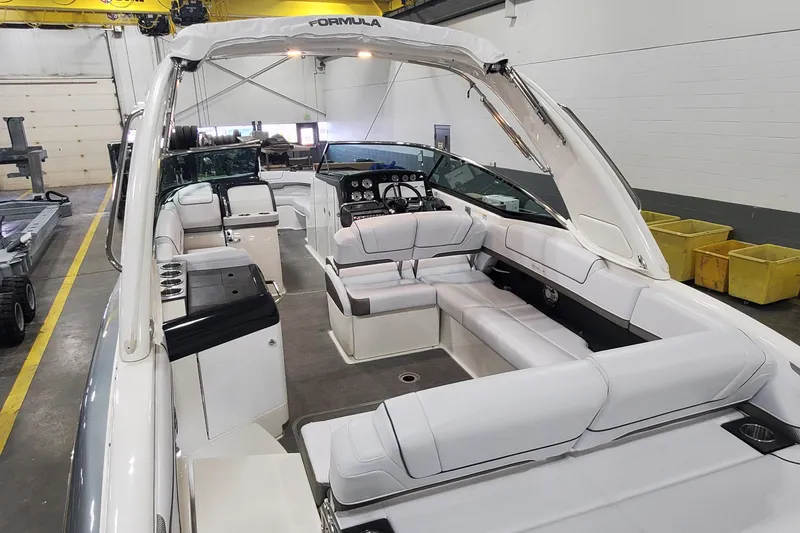 Slide: The Image of 2017 Formula 310 Bowrider boat interior with white seating in a warehouse setting. - 6