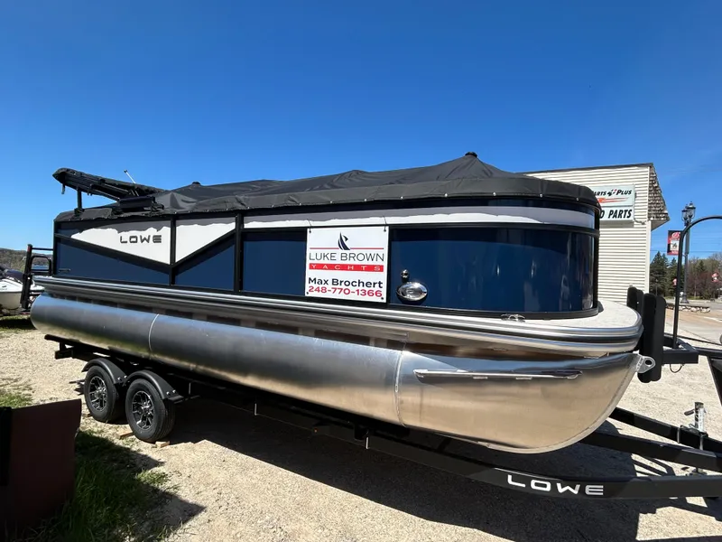 The Image of 2025 Lowe LS210WT pontoon boat on trailer, covered and parked outdoors. - 0