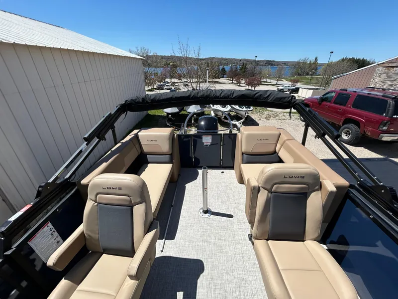 Slide: The Image of 2025 Lowe LS210WT boat interior with beige seating and steering console. - 2