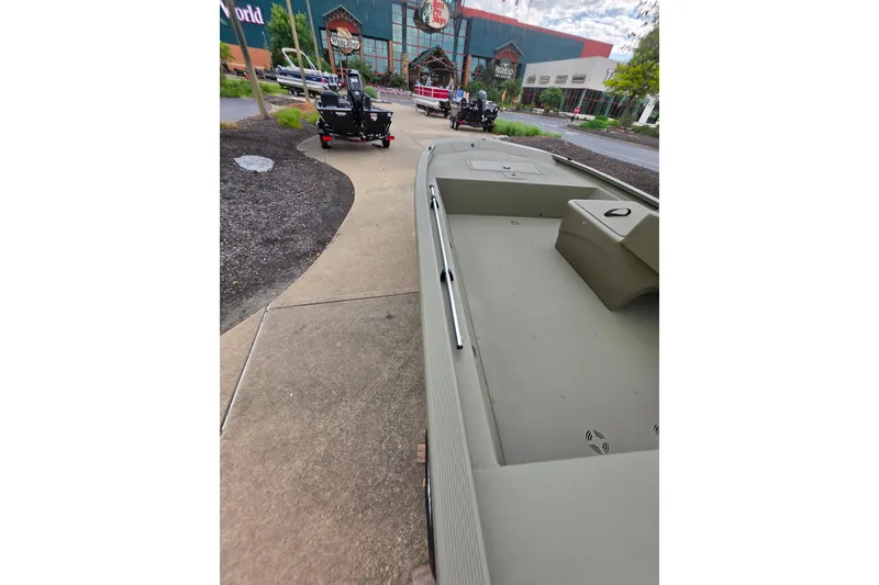 Slide: The Image of 2026 Tracker Grizzly 1648 SC boat displayed outdoors near a store entrance. - 4
