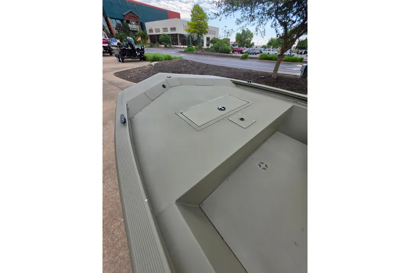 Slide: The Image of 2026 Tracker Grizzly 1648 SC boat displayed outdoors near a store. - 8
