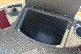 Slide: The Image of 2026 Sun Tracker Bass Buggy 18 DLX storage compartment with cup holders and carpeted flooring. - 16