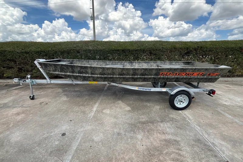 The Image of 2026 Tracker Grizzly 15 Jon boat on trailer, parked outdoors under cloudy sky. - 0