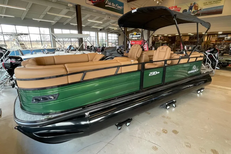 The Image of 2026 Regency 230 DL pontoon boat with tan seating and green exterior in showroom. - 1