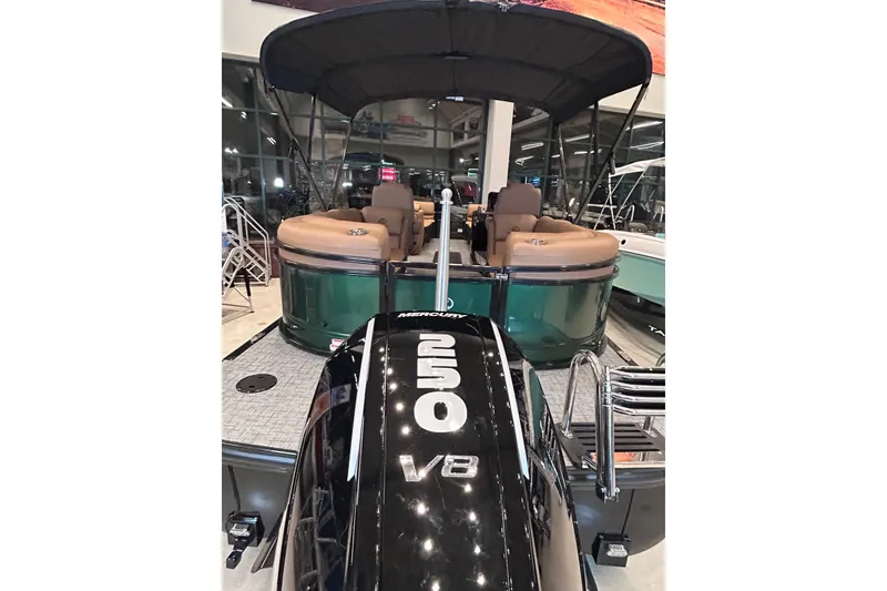Slide: The Image of 2026 Regency 230 DL pontoon boat with Mercury 250 V8 engine, showcased indoors. - 10