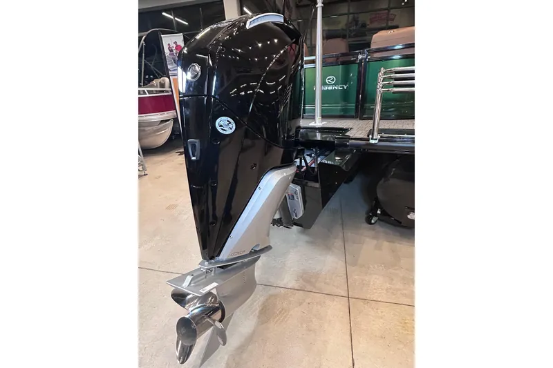 Slide: The Image of 2026 Regency 230 DL boat with a sleek black outboard motor in showroom. - 11