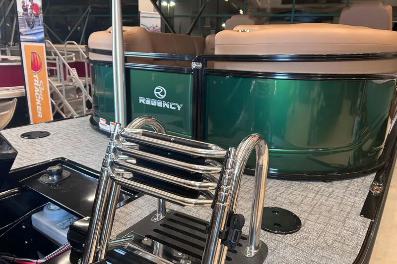 Slide: The Image of 2026 Regency 230 DL boat with green exterior and chrome ladder in showroom. - 13