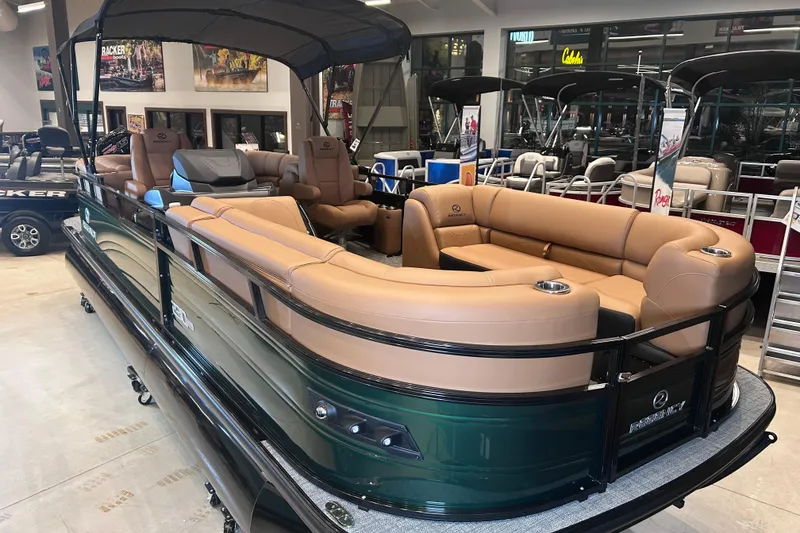 Slide: The Image of 2026 Regency 230 DL pontoon boat with tan seating and black canopy in showroom. - 14