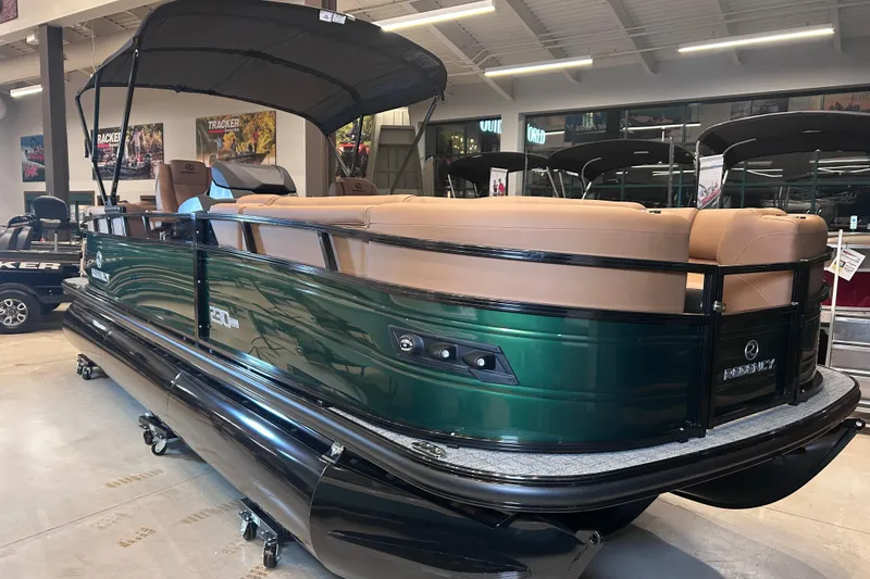 Slide: The Image of 2026 Regency 230 DL pontoon boat with tan seating and green exterior in showroom. - 15