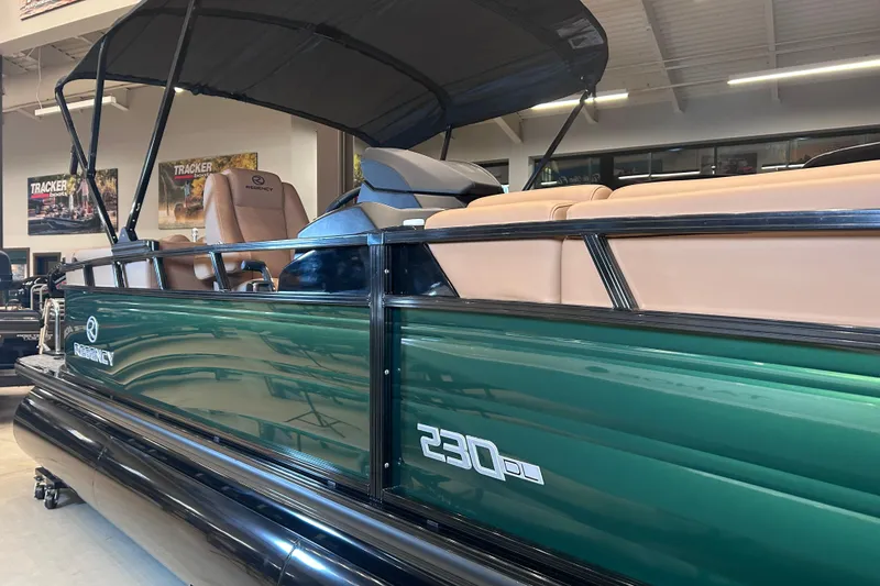 Slide: The Image of 2026 Regency 230 DL pontoon boat with green exterior and tan seating in showroom. - 16